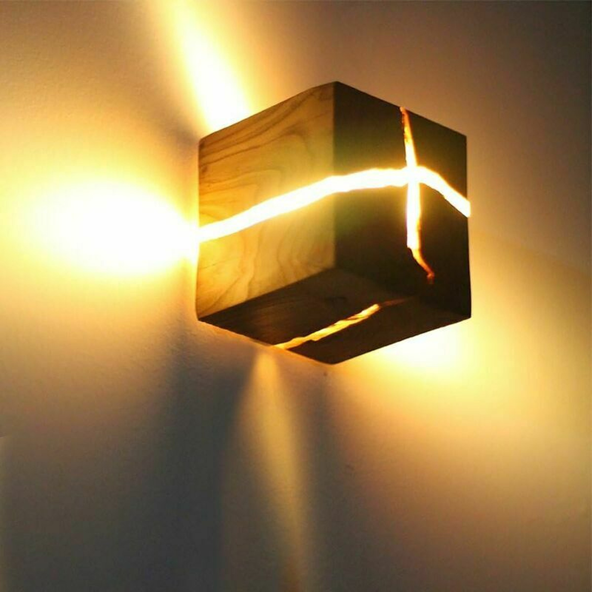 Eine Holzklotz-Wandlampe mit leuchtenden Rissen wirft warmes Licht an eine schlichte Wand.