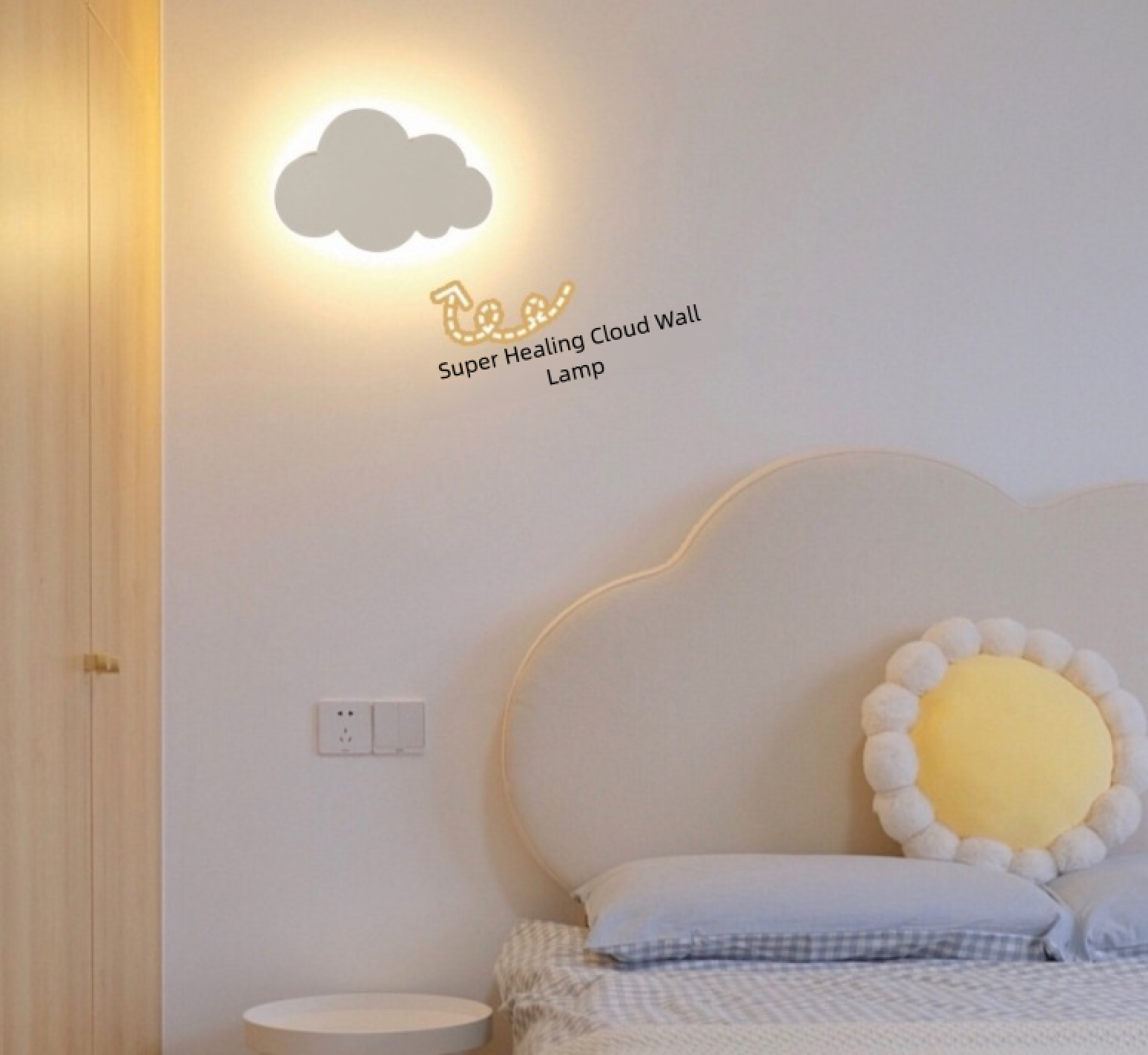 Eine wolkenförmige Wandlampe leuchtet an einer hellen Wand über einem Bett mit einem sonnenförmigen Kissen.