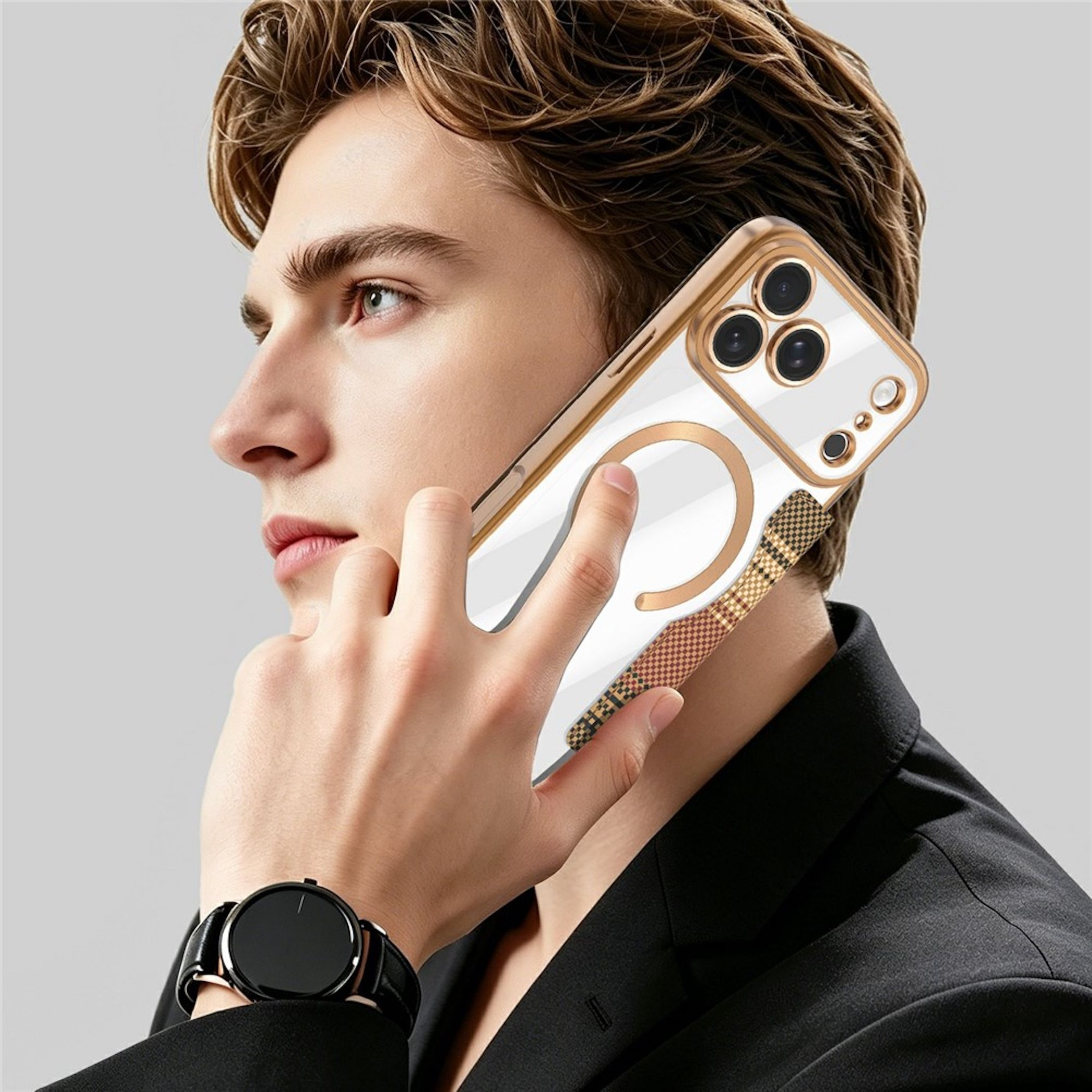 Ein Mann mit schwarzem Anzug und Armbanduhr hält ein Smartphone mit goldener Hülle und Ringhalter ans Ohr.