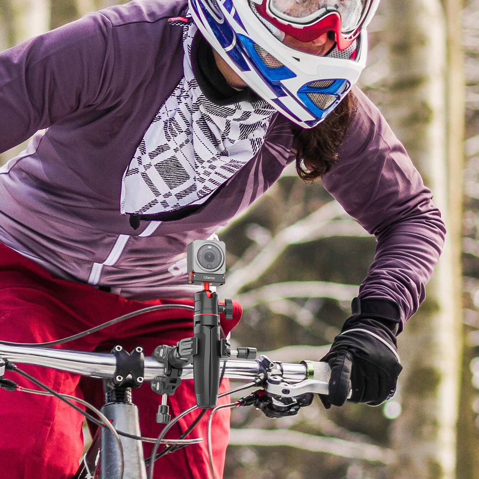 Un mountain biker in abbigliamento protettivo guida in un bosco, con una action cam sul manubrio.
