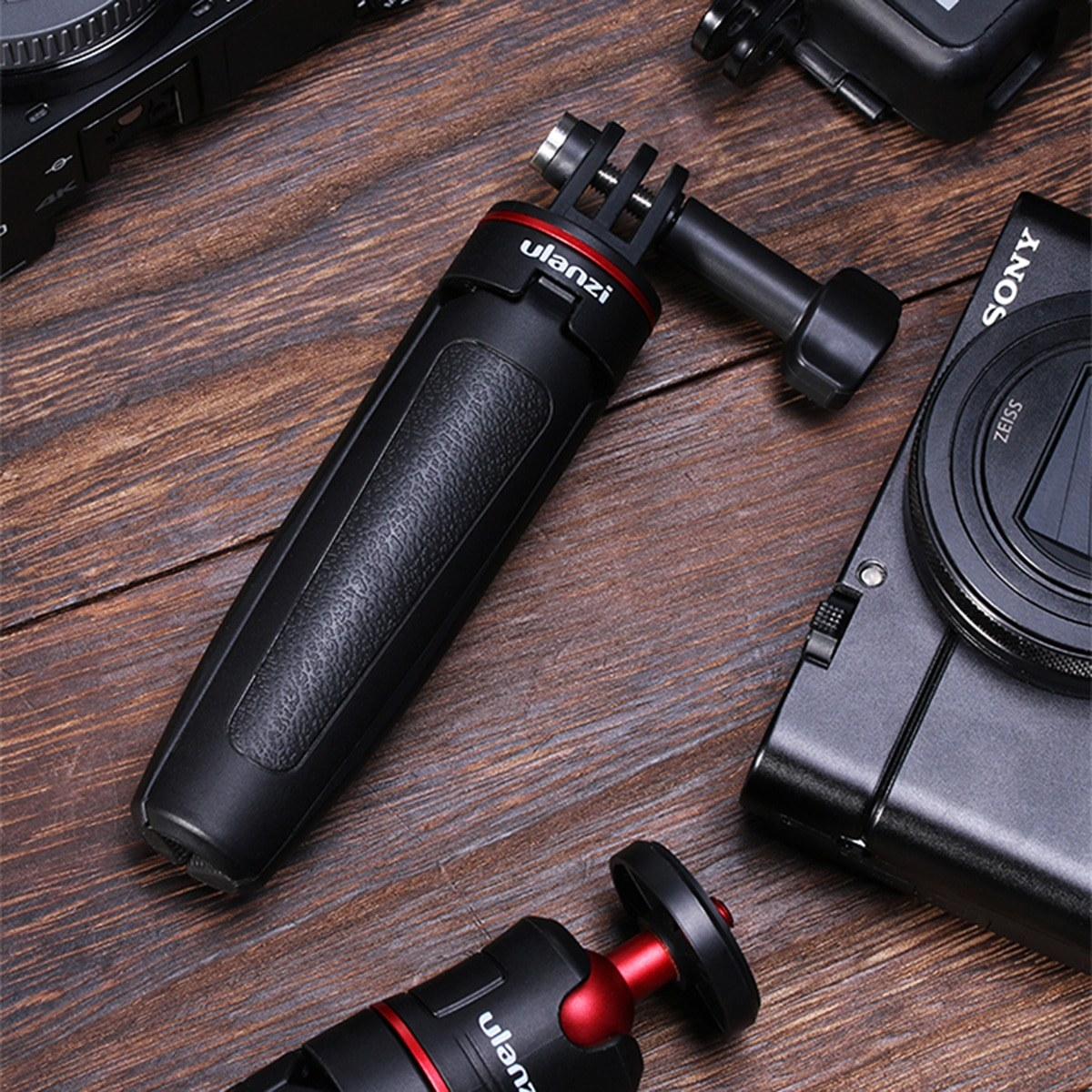 Czarny uchwyt do aparatu Ulanzi leży na drewnianym stole obok aparatu Sony.
