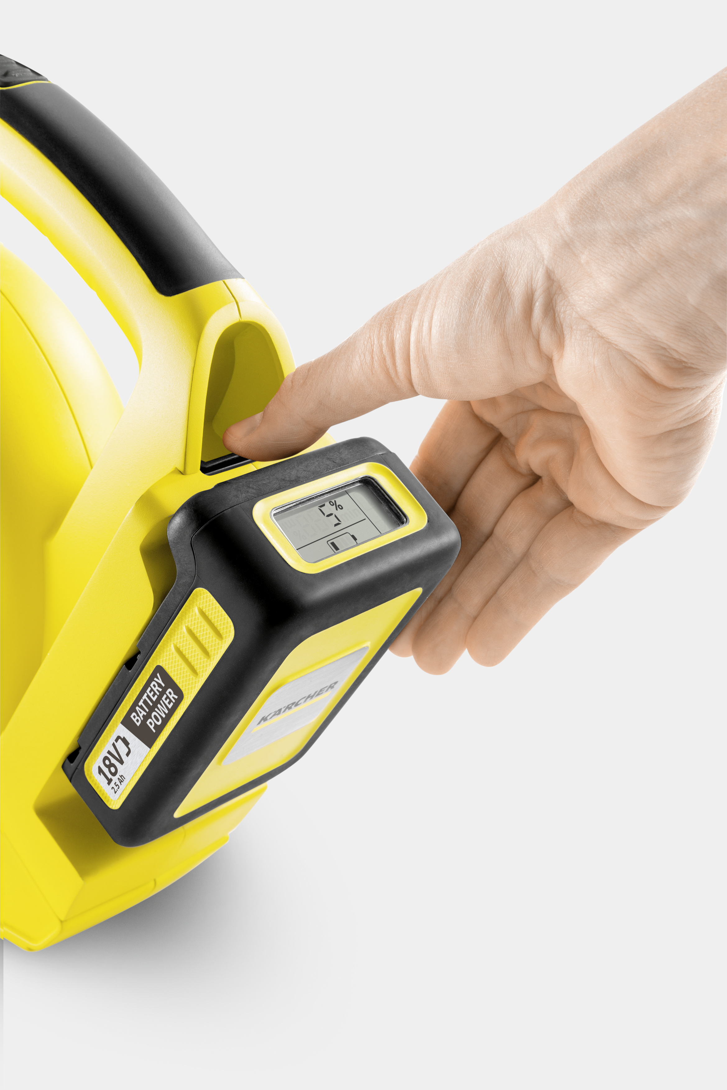 Una mano inserta una batería Karcher amarilla y negra de 18V con pantalla en un dispositivo.