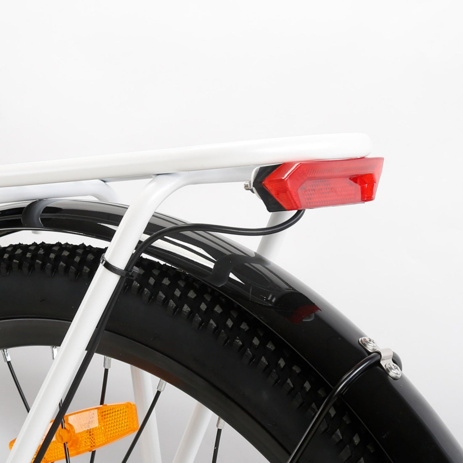 Primo piano del portapacchi posteriore, luce rossa, parafango nero e pneumatico di una bici su sfondo bianco.