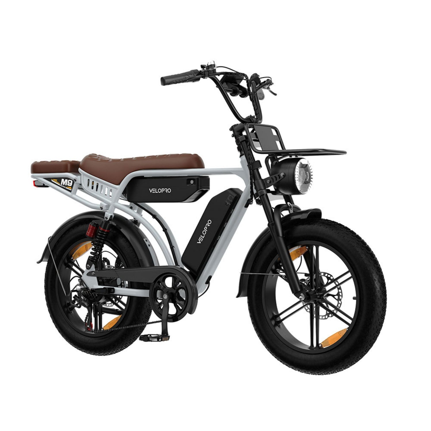 Una bici elettrica Velopro grigia con sella in pelle marrone, pneumatici larghi, faro anteriore e portapacchi su sfondo bianco.