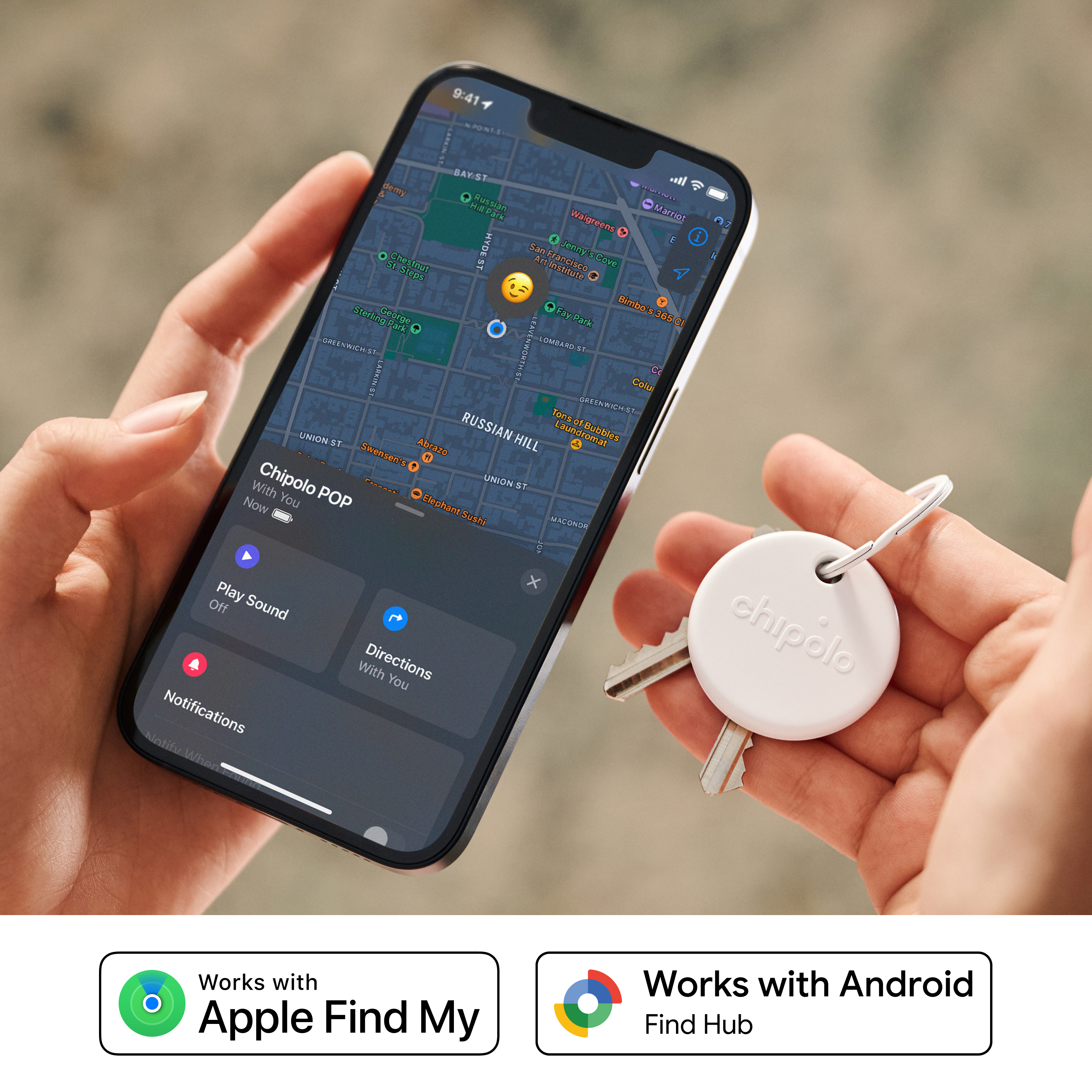 Une personne tient un smartphone avec une appli de carte et un traceur blanc sur un porte-clés.