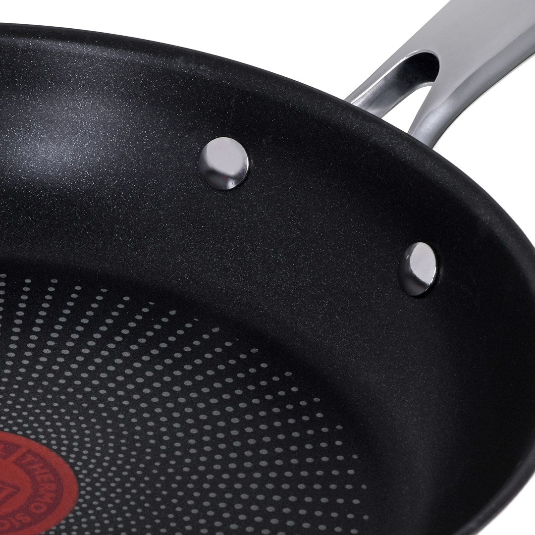 Close-up of a black non-stick frying pan with a riveted silver handle and pattern.