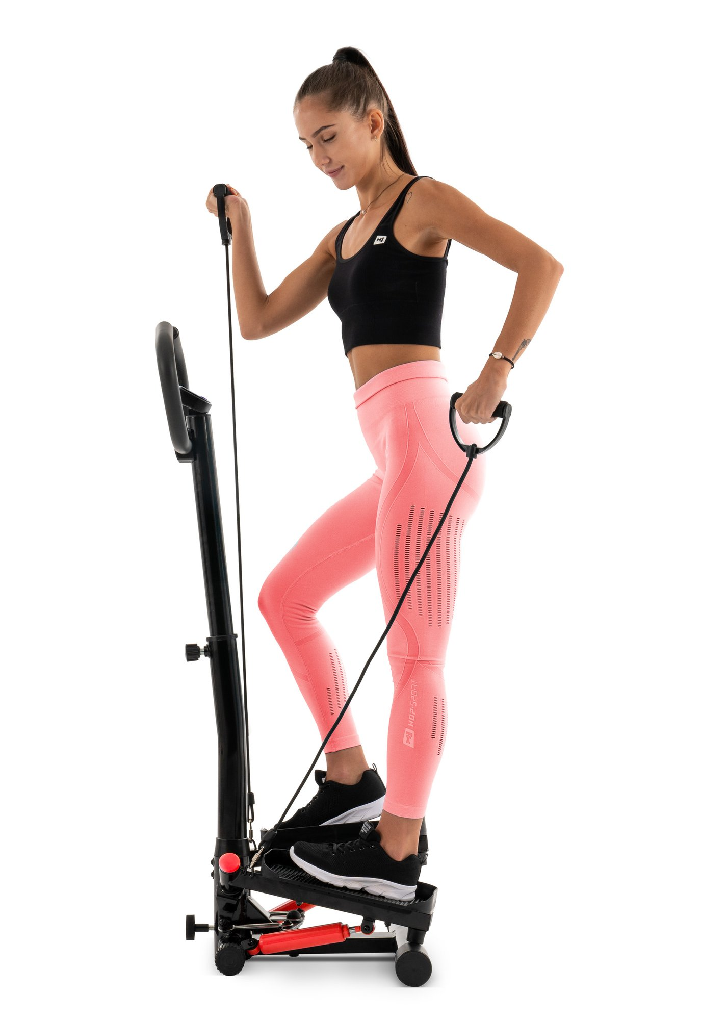 Eine Frau in Sportkleidung trainiert auf einem schwarzen Stepper mit Widerstandsbändern vor weißem Hintergrund.