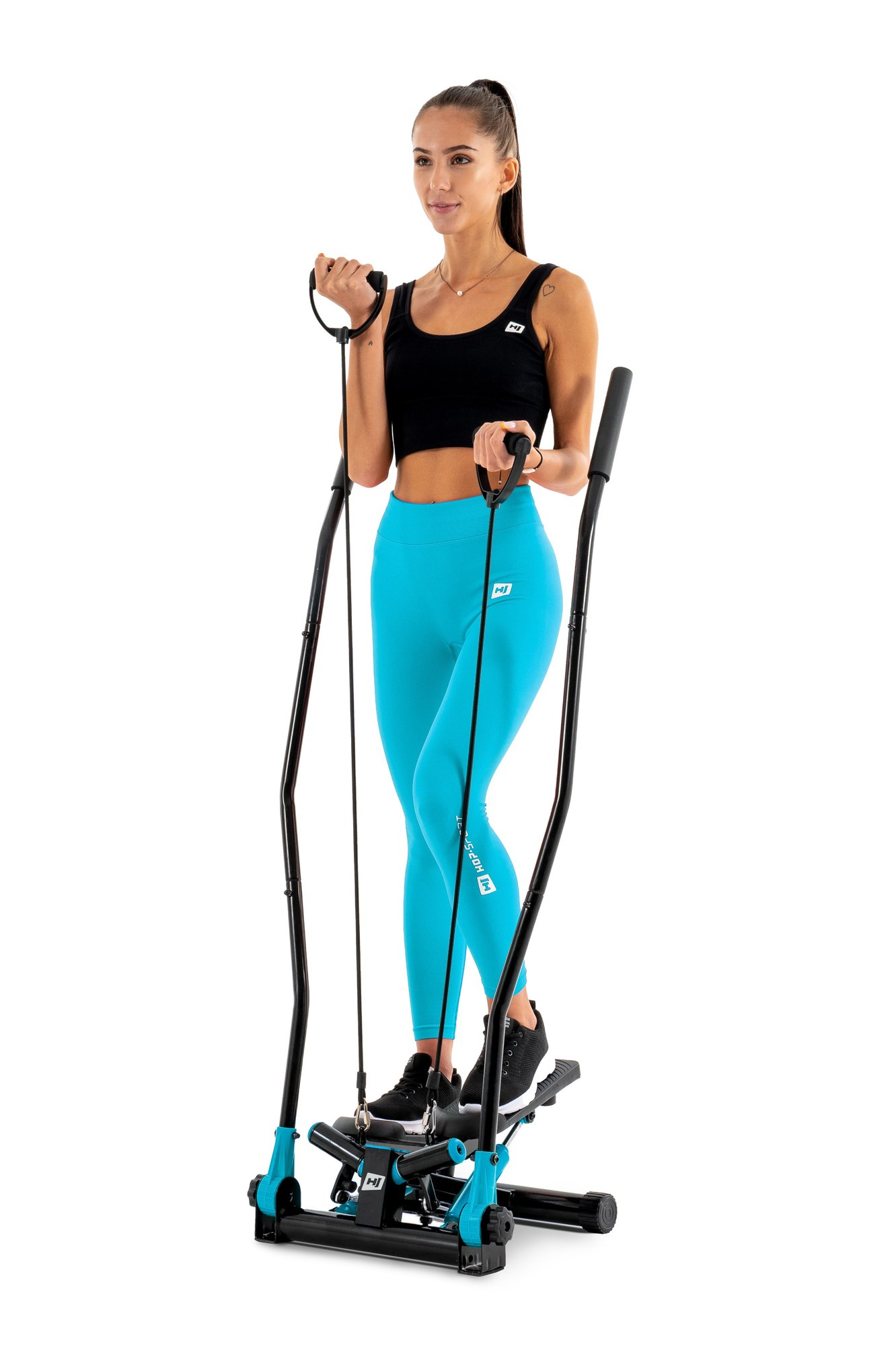 Eine Frau im schwarzen Oberteil und blauen Leggings trainiert auf einem Stepper vor weißem Hintergrund.