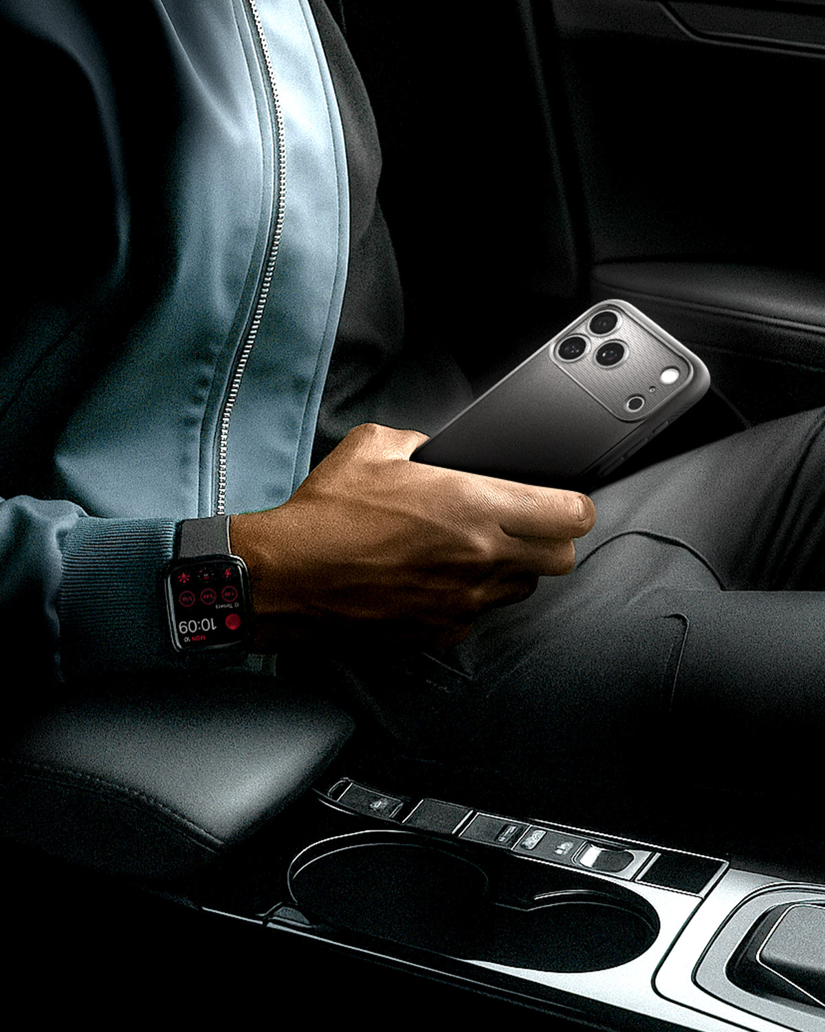 Een persoon in een auto, draagt een smartwatch en houdt een smartphone vast.