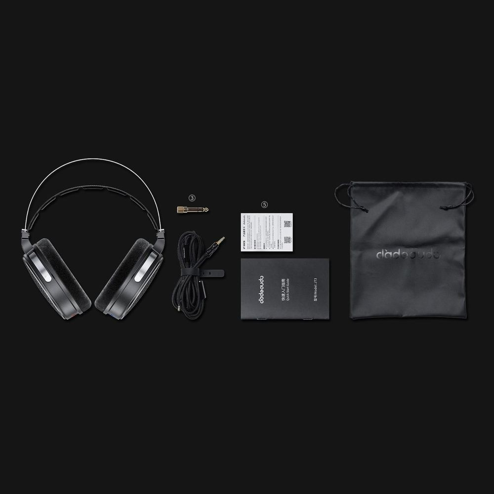 Czarne słuchawki, kabel audio, adapter, instrukcje i etui rozłożone na ciemnym tle.