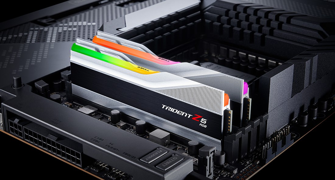 Dos módulos de RAM Trident Z5 RGB con disipadores plateados están instalados en una placa base negra.