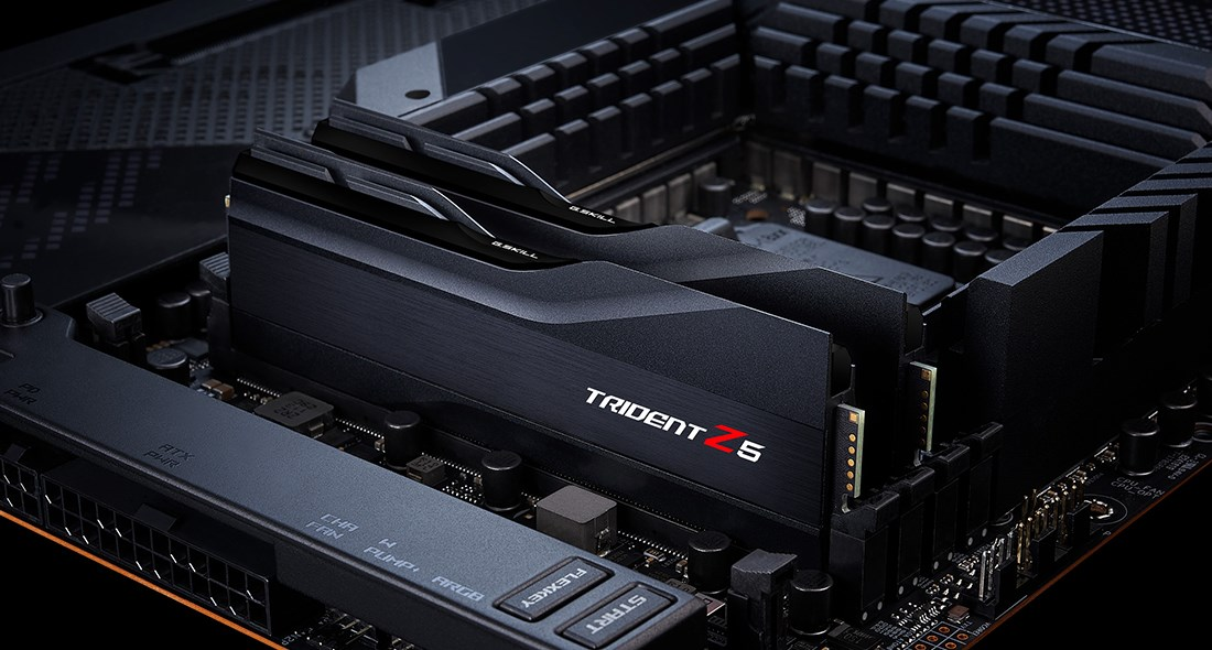 Gros plan sur les barrettes de RAM noires G.SKILL Trident Z5 sur une carte mère sombre.