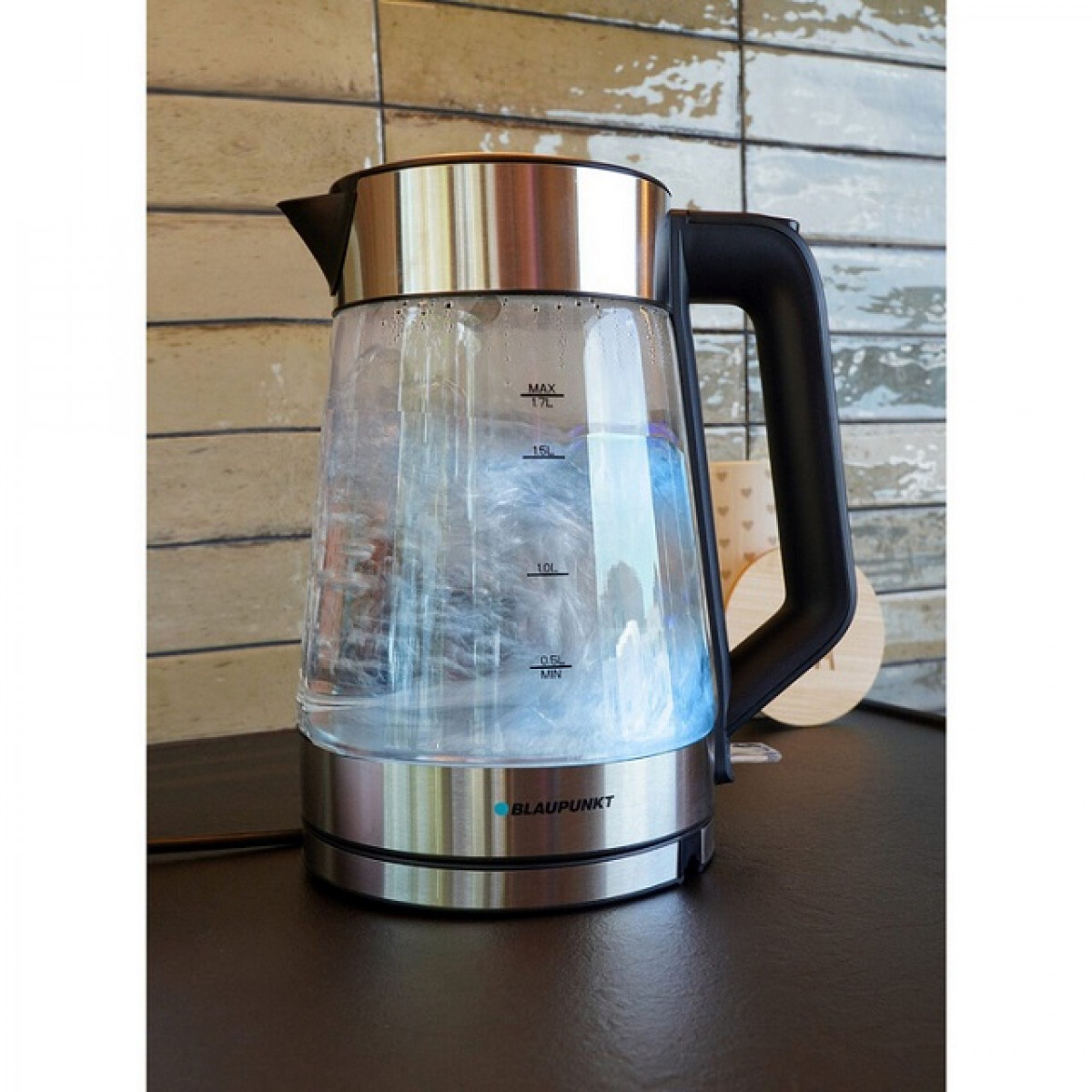 Un bollitore elettrico in vetro con acqua bollente su un bancone.