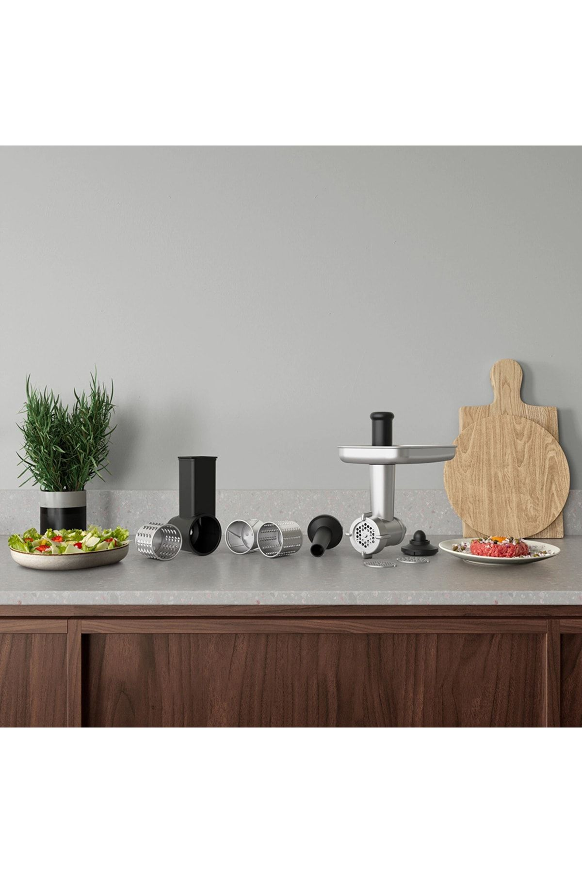 Piano cucina con insalata, pianta, accessori per tritacarne, tritacarne e taglieri in legno.