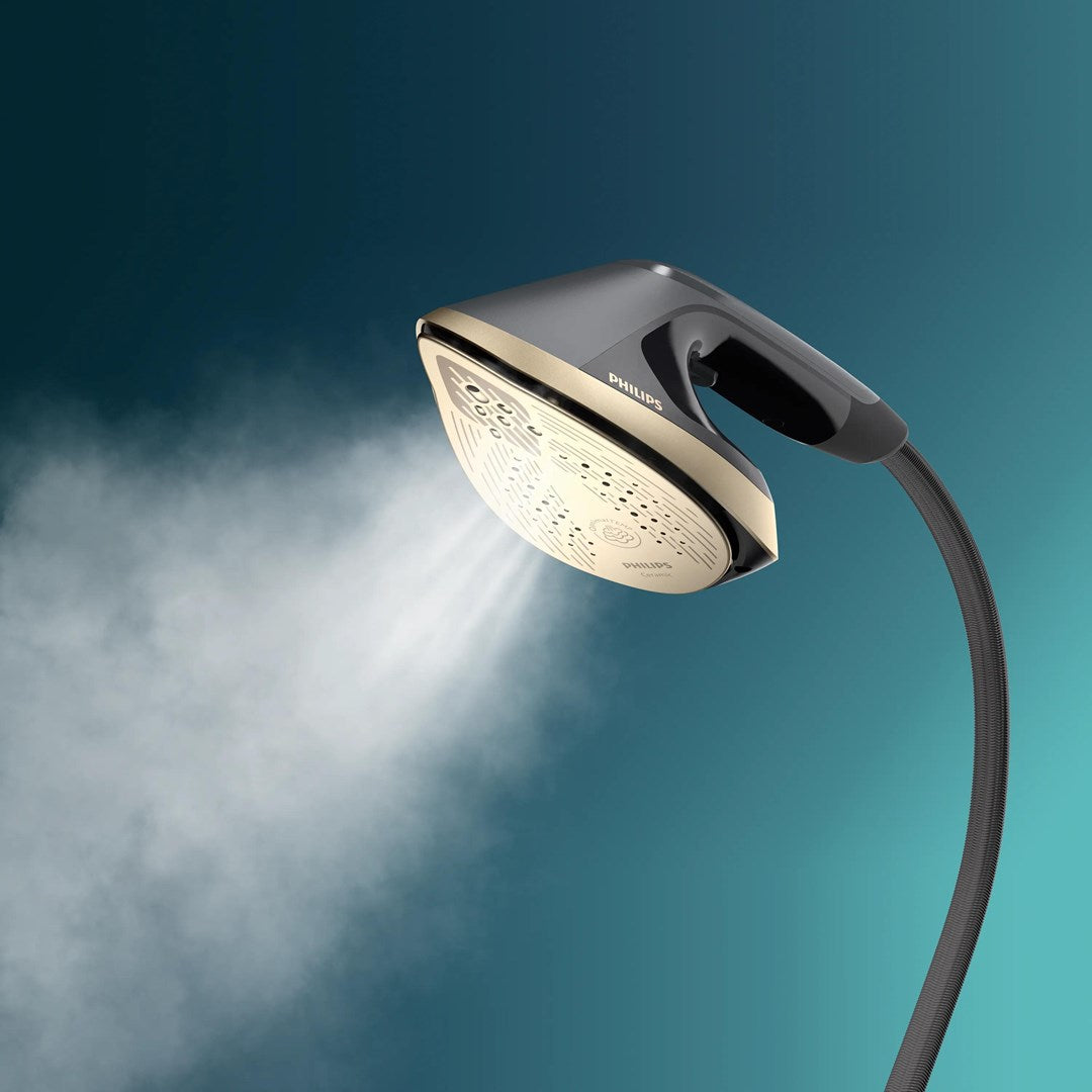 Turkuaz gradyan arka plan önünde buhar çıkaran siyah ve altın renkli Philips giysi buharlayıcısı.