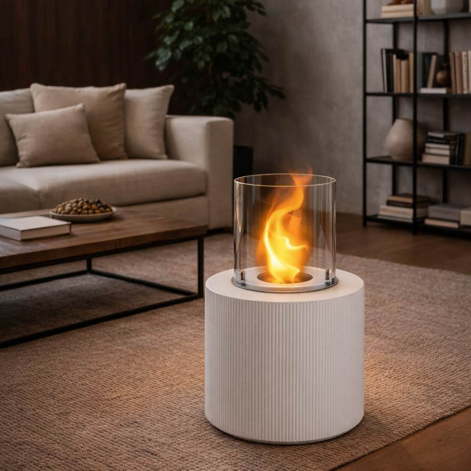 Un caminetto da tavolo cilindrico bianco con una fiamma viva si trova in un accogliente soggiorno.
