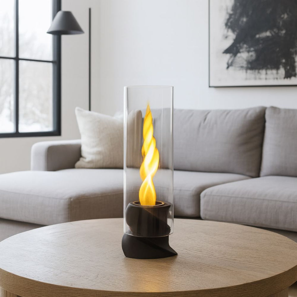 Un cilindro di vetro con una fiamma gialla a spirale si trova su un tavolino in legno in un soggiorno.