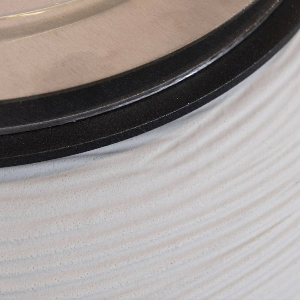 Primo piano di un vaso bianco texturizzato con bordo nero e coperchio metallico argentato.