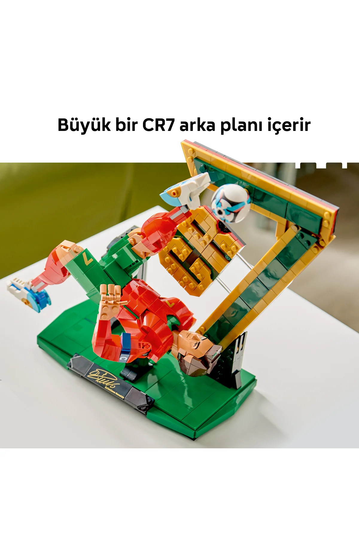 Bir Lego modeli, kırmızı ve yeşil formasıyla kale yapısı yanında röveşata çeken bir oyuncuyu gösteriyor.
