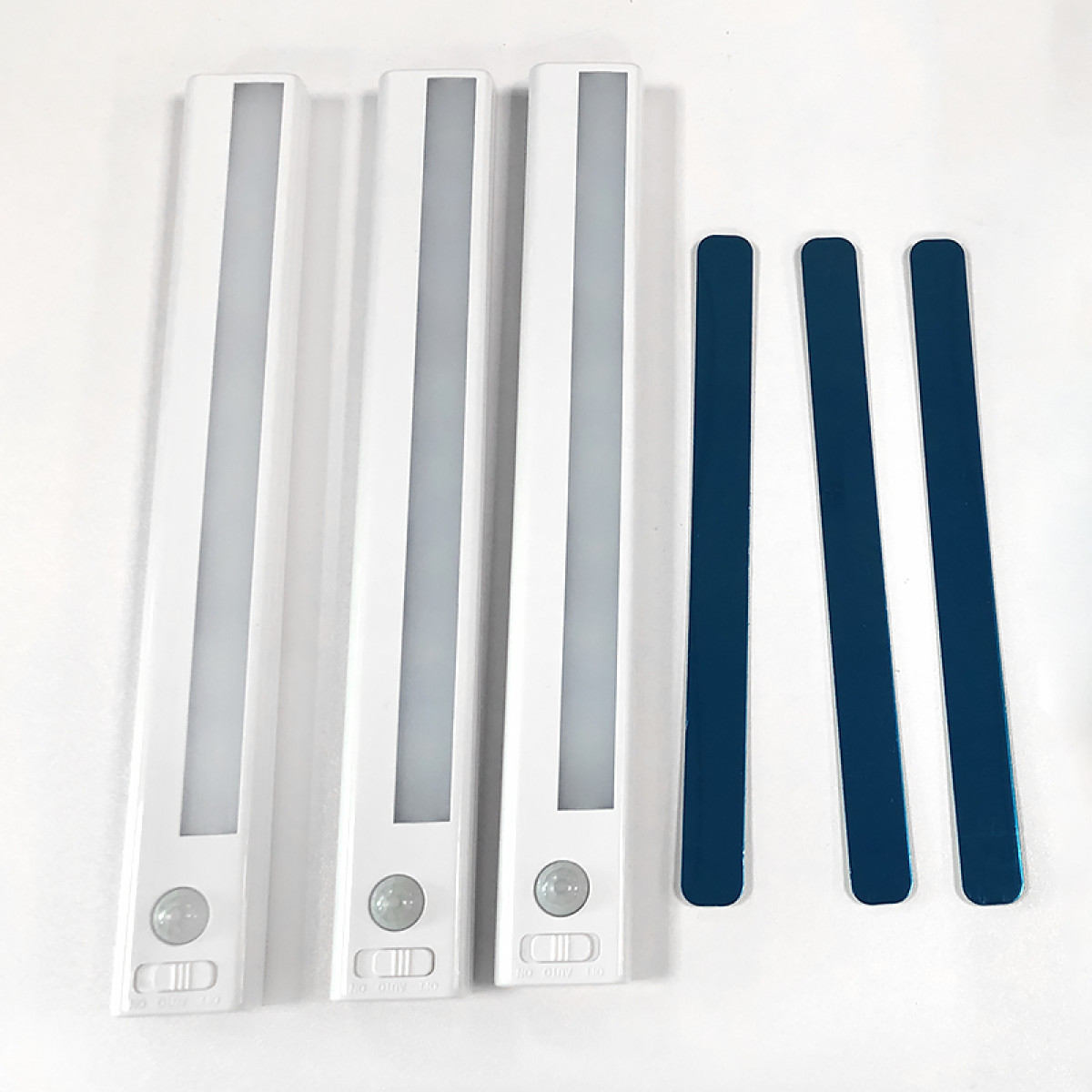 Tre luci LED bianche con sensore di movimento accanto a tre strisce magnetiche.