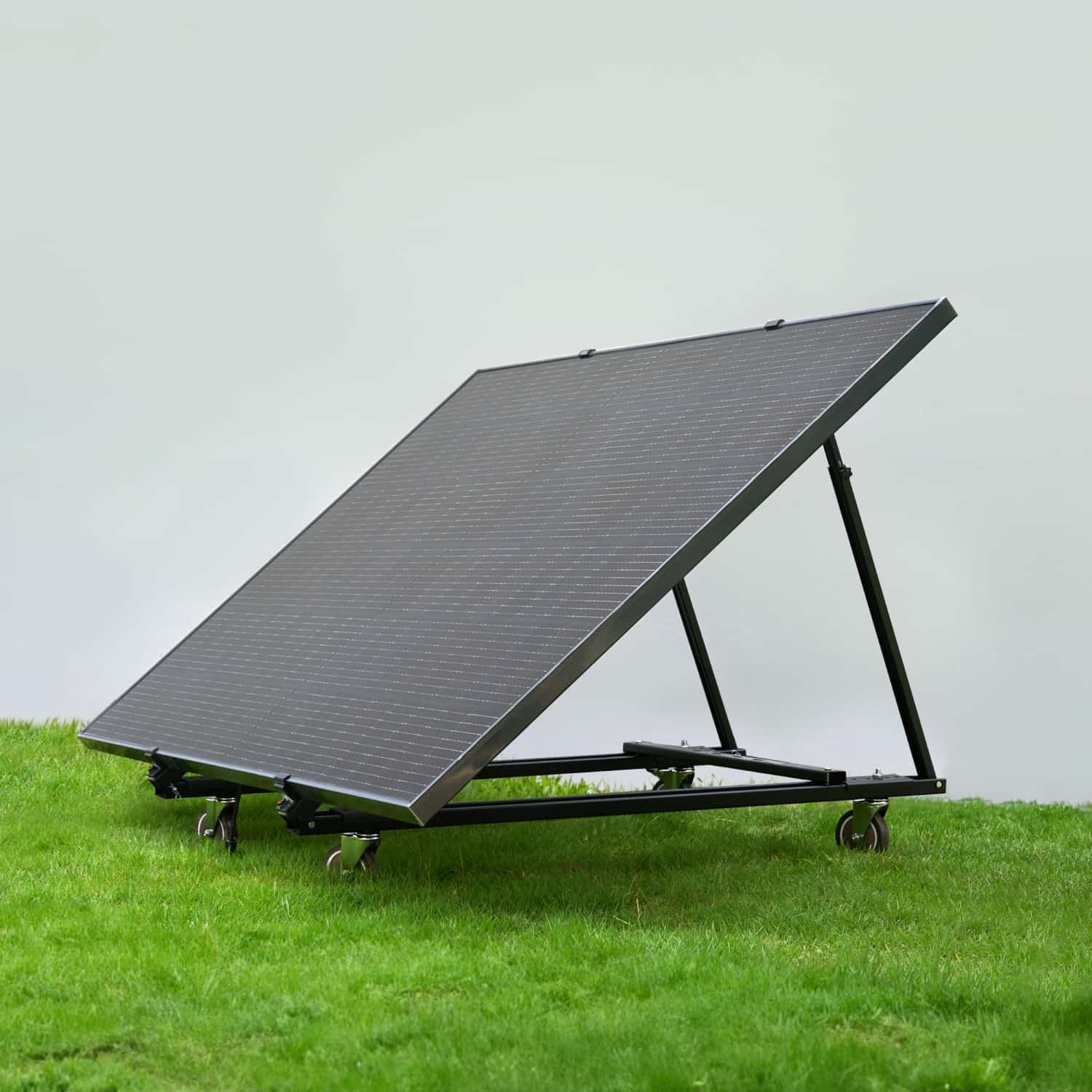 Un pannello solare nero su supporto con ruote posato sull'erba verde.