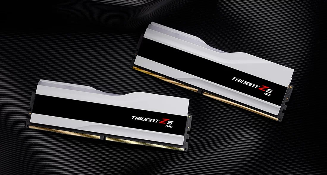 Siyah şeritli iki beyaz Trident Z5 RGB RAM çubuğu, tırtıklı siyah arka plan üzerinde.