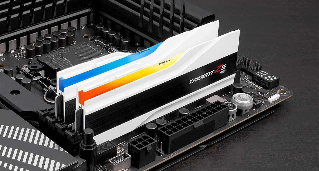 Bir anakart üzerine takılı, mavi ve turuncu detaylı iki beyaz Trident Z5 RGB RAM.
