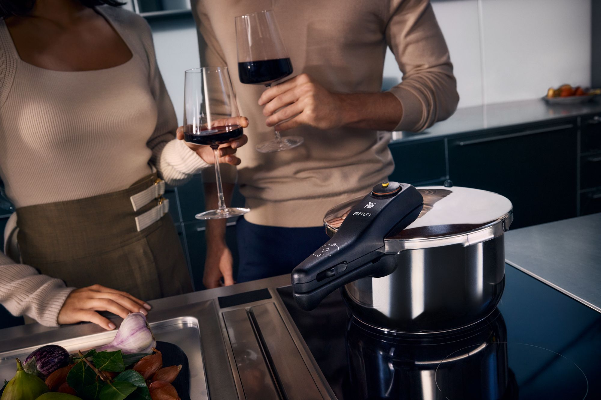 Coppia con bicchieri di vino in cucina vicino a una pentola a pressione.