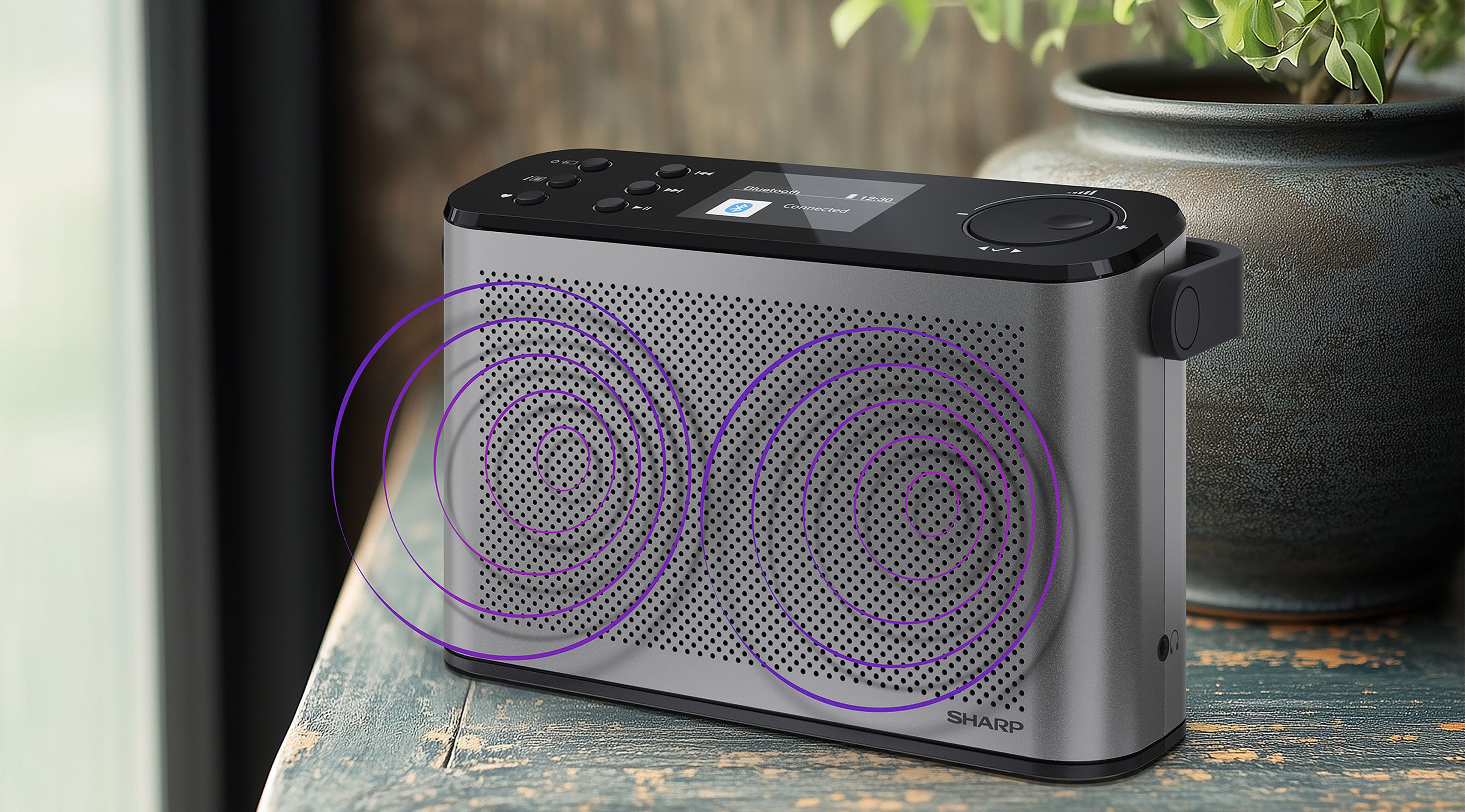 Ein silbernes Sharp-Radio mit violetten Schallwellen-Grafiken steht auf einem rustikalen Holztisch.