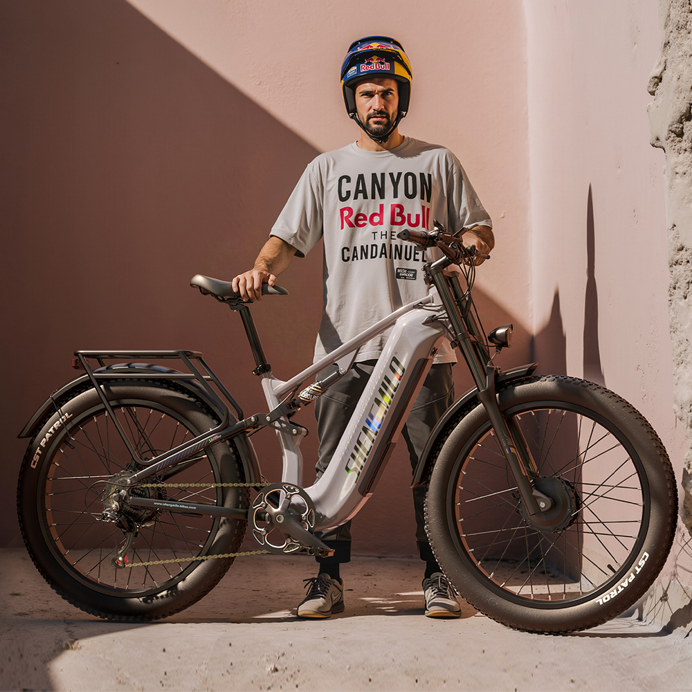 Un hombre con casco está junto a una bicicleta eléctrica gris contra una pared rosa.