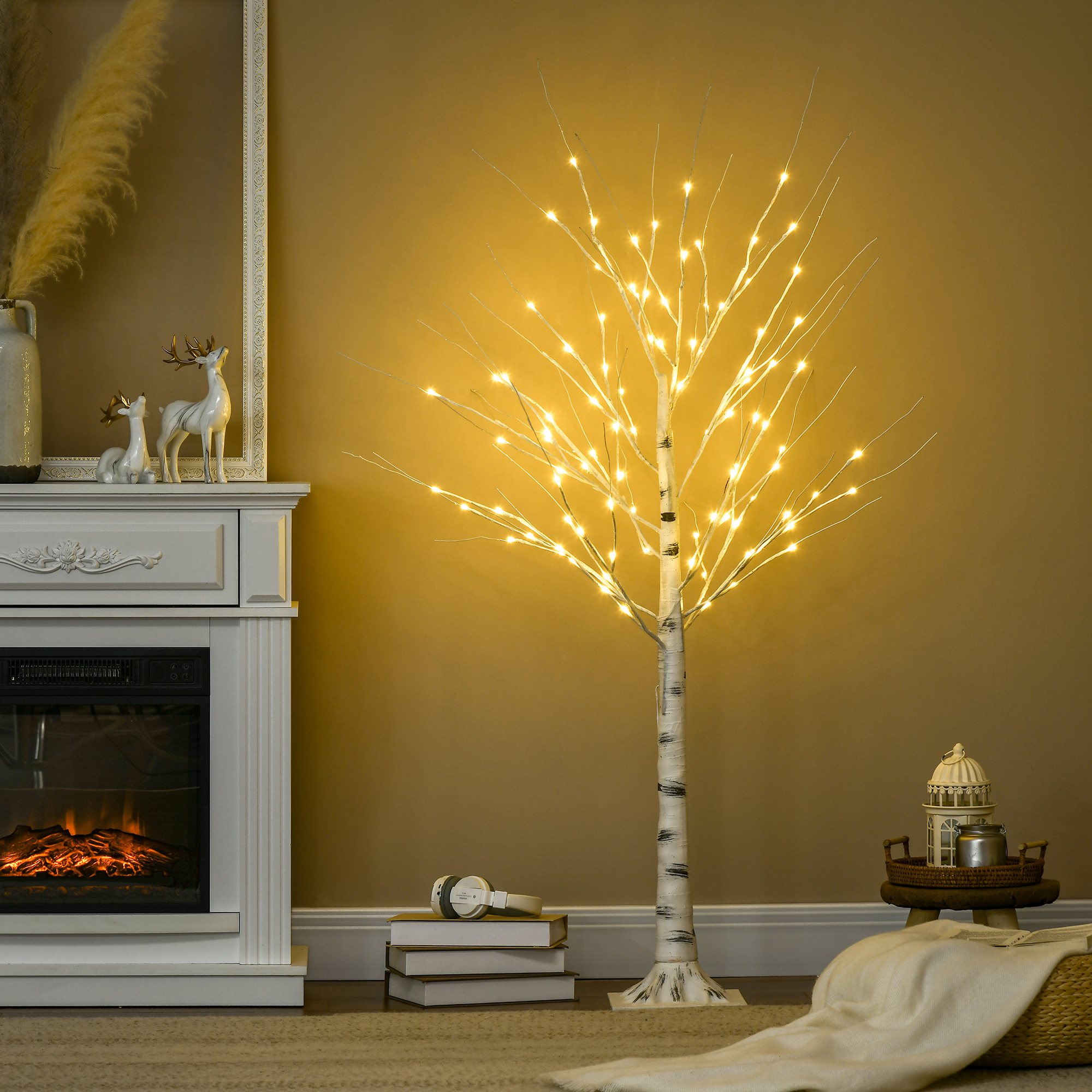 Árbol artificial iluminado junto a una chimenea, con libros y un farol.