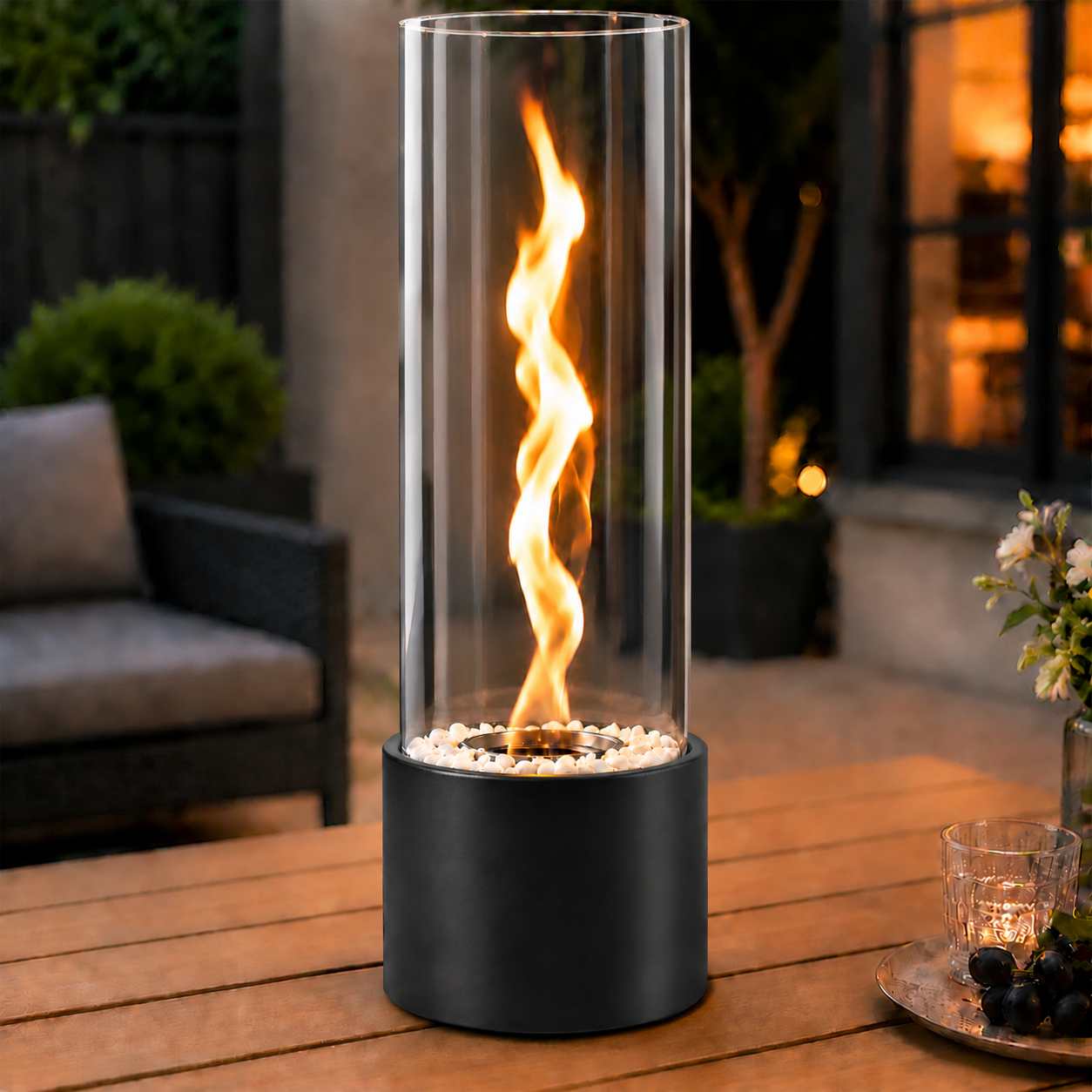 Ein zylindrischer Tischkamin mit offener Flamme steht auf einem Holzstuhl im Freien.