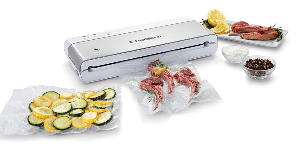 Zgrzewarka próżniowa FoodSaver pakuje mięso i cukinię, w otoczeniu soli, pieprzu i surowego mięsa.