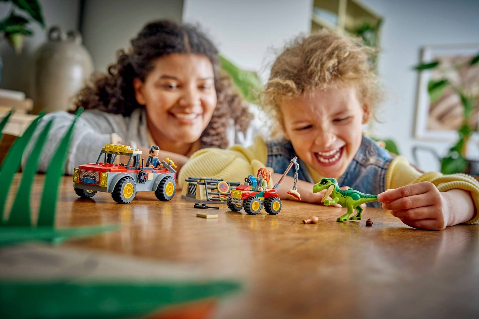 Una donna e un bambino giocano felicemente con dinosauri Lego e veicoli giocattolo.