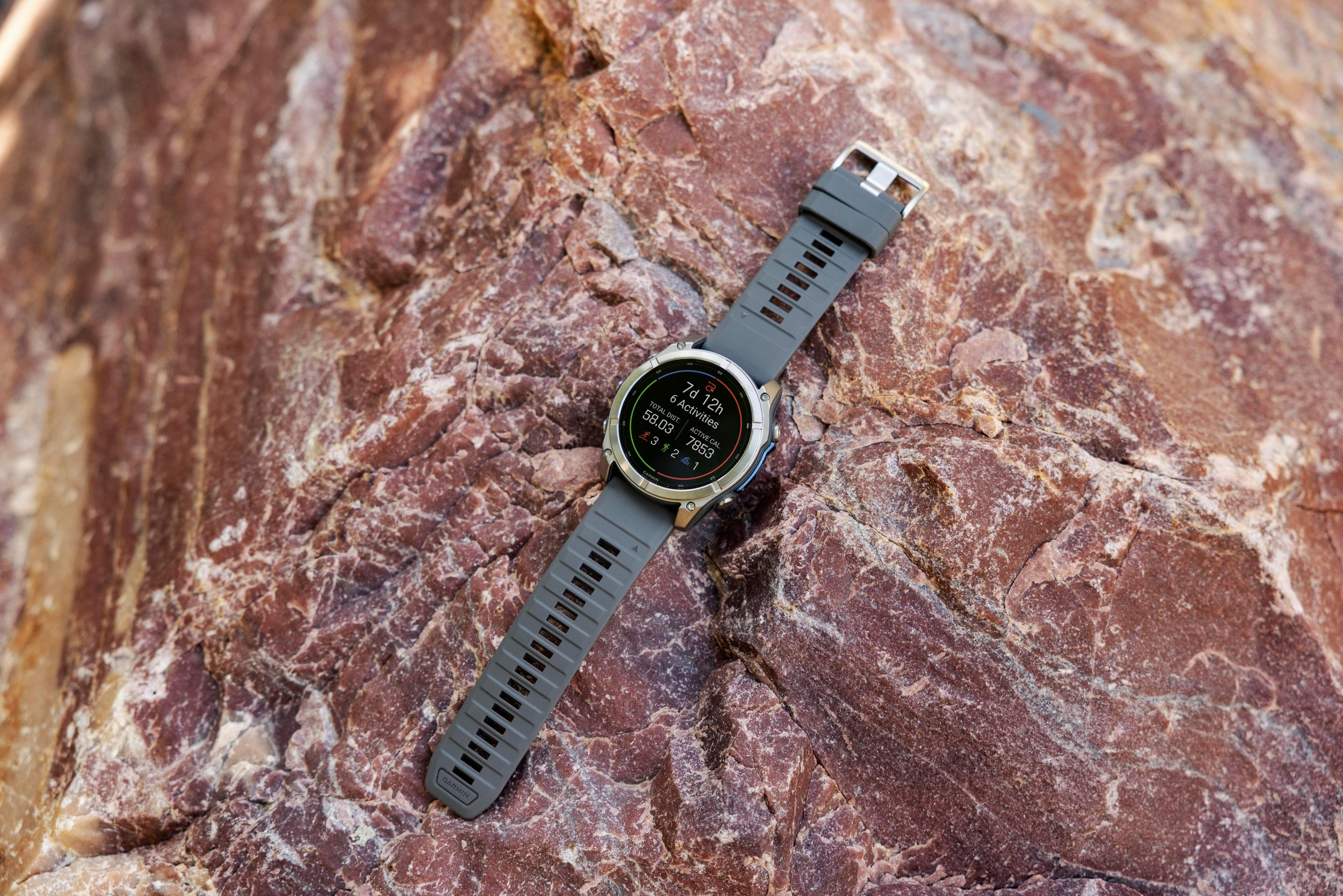 Un orologio sportivo grigio con display digitale si trova su una roccia rossa.