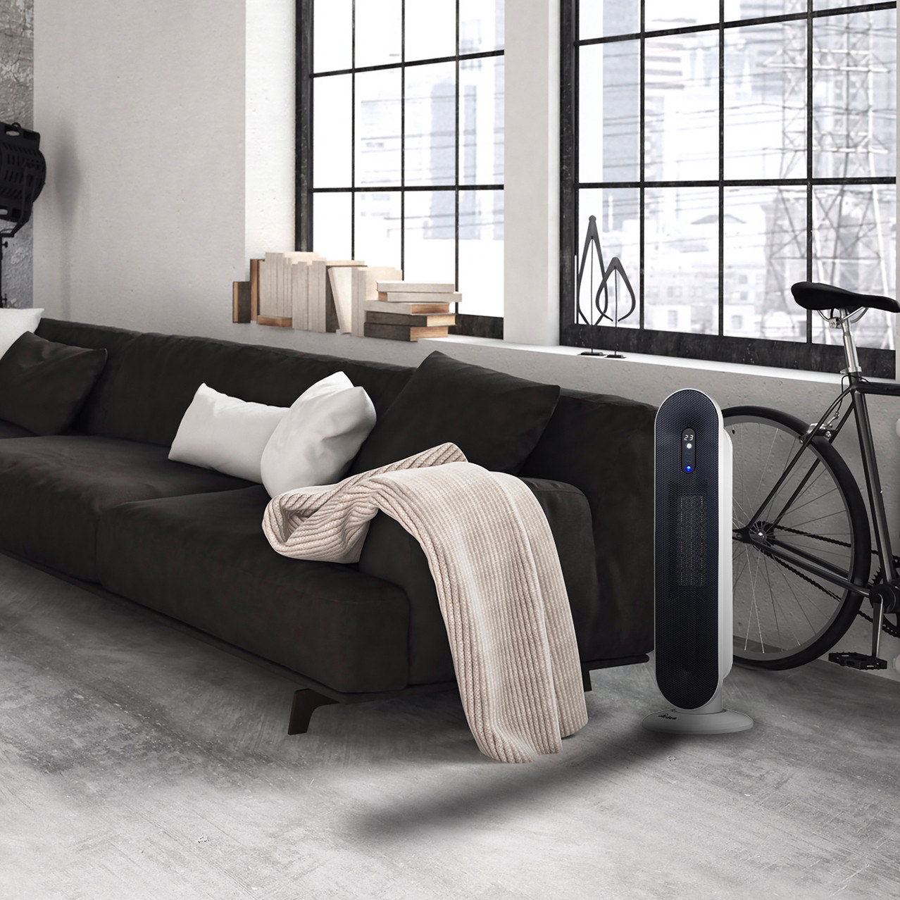 Moderno soggiorno in stile loft con divano scuro, coperta chiara, termoventilatore e bicicletta vicino alla finestra.