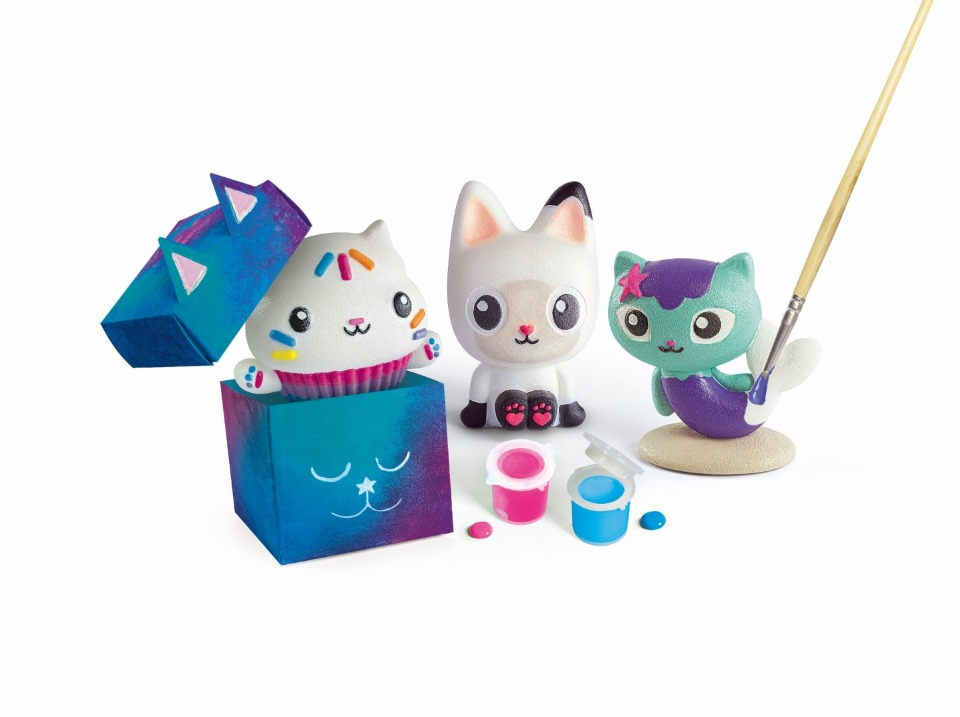 Tres figuras de gatos, dos tarros de pintura y un pincel sobre fondo blanco. Un gato está dentro de una caja de regalo.