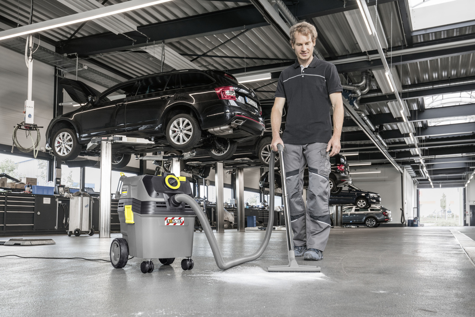 Ein Mechaniker nutzt einen Industriesauger in einer großen Werkstatt.