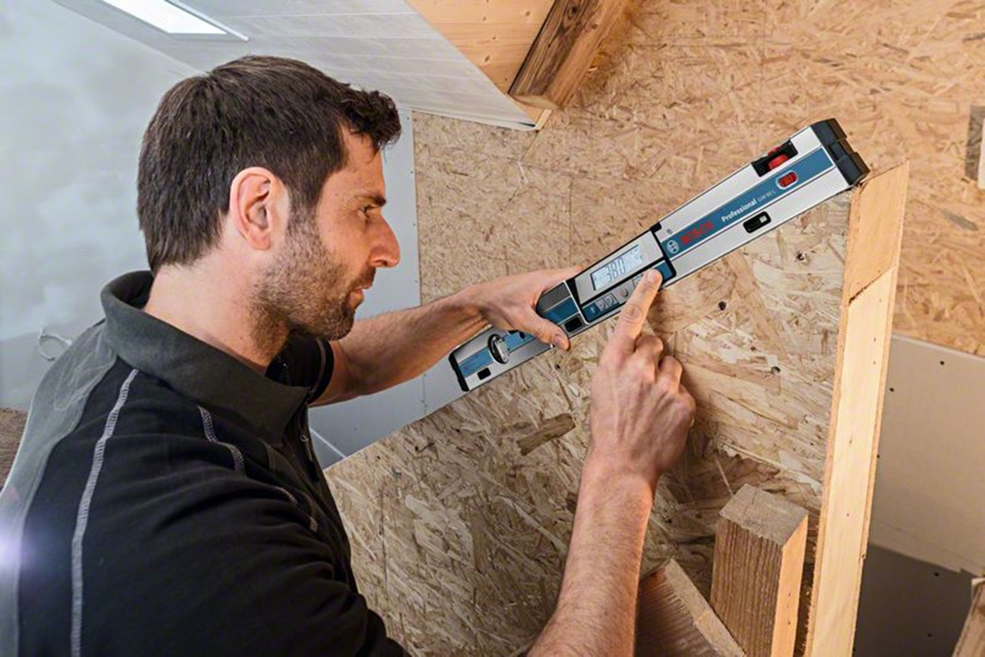 Bir zanaatkar dijital Bosch açı ölçer kullanarak tahta üzerinde açı ölçüyor.