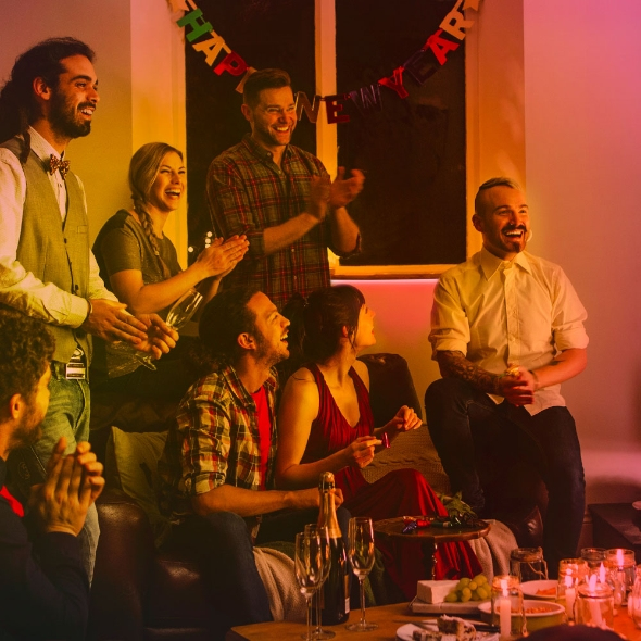 Amigos celebrando juntos en una habitación iluminada cálidamente con una pancarta.
