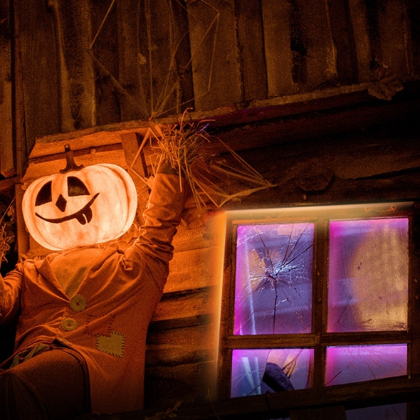 Un espantapájaros de Halloween con cabeza de calabaza brillante y abrigo naranja está junto a una ventana rota.