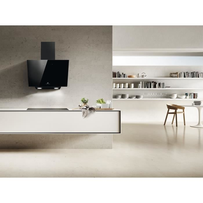 Cocina moderna con campana extractora negra sobre barra blanca y estanterías con libros al fondo.