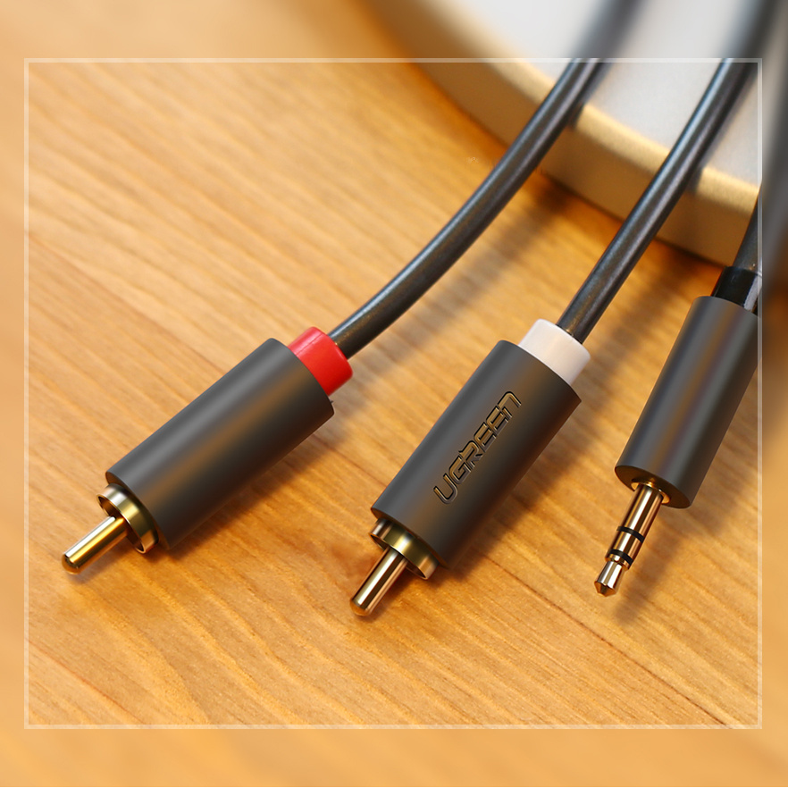 Trzy kable audio ze złoconymi złączami na drewnianym stole.