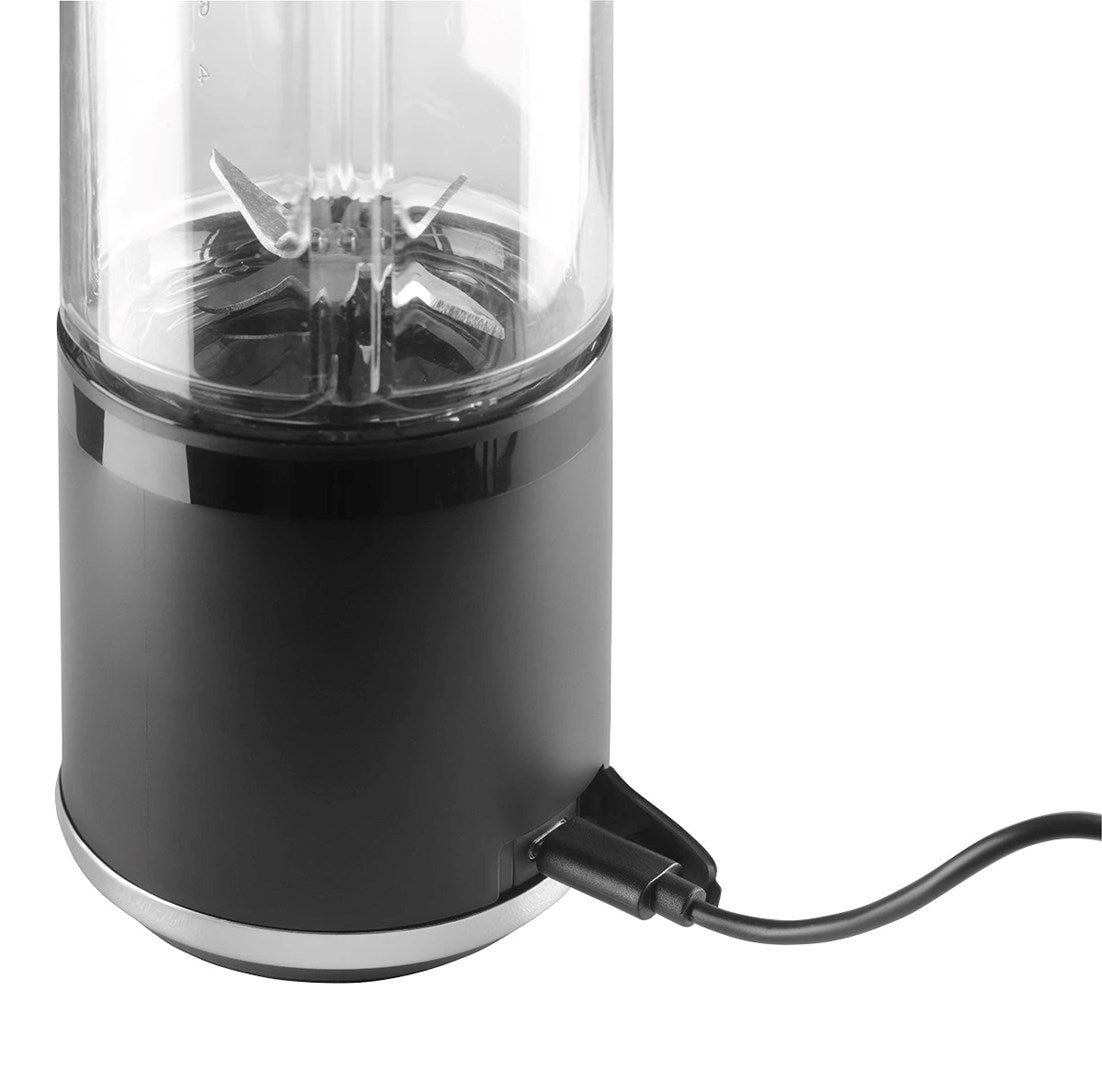 Przenośny blender z czarną podstawą i kablem ładującym na białym tle.