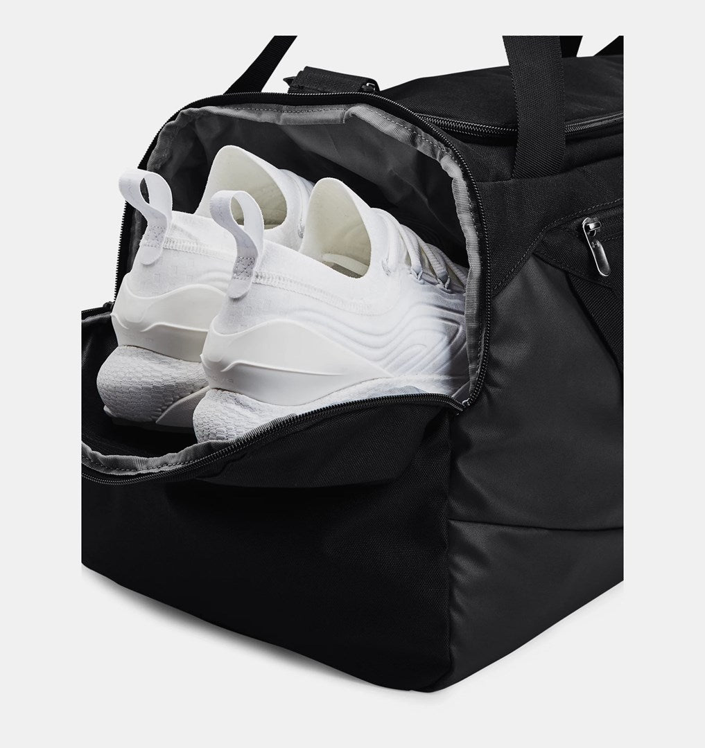 Eine schwarze Sporttasche mit weißen Sneakers im belüfteten Seitenfach.