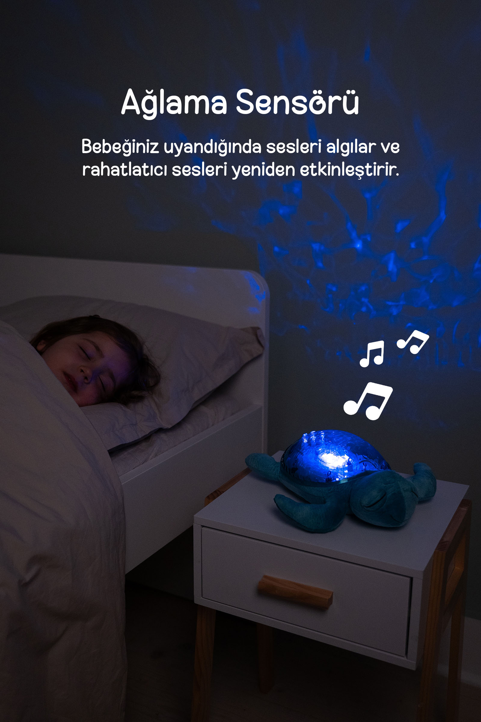 Yatakta uyuyan bir çocuğun yanında duvara mavi ışık yansıtan sevimli bir kaplumbağa gece lambası.