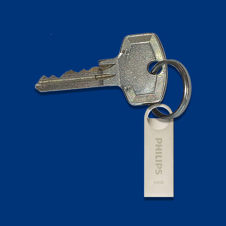 Een zilveren sleutel met een sleutelhanger aan een Philips 64GB USB-stick, tegen een donkerblauwe achtergrond.