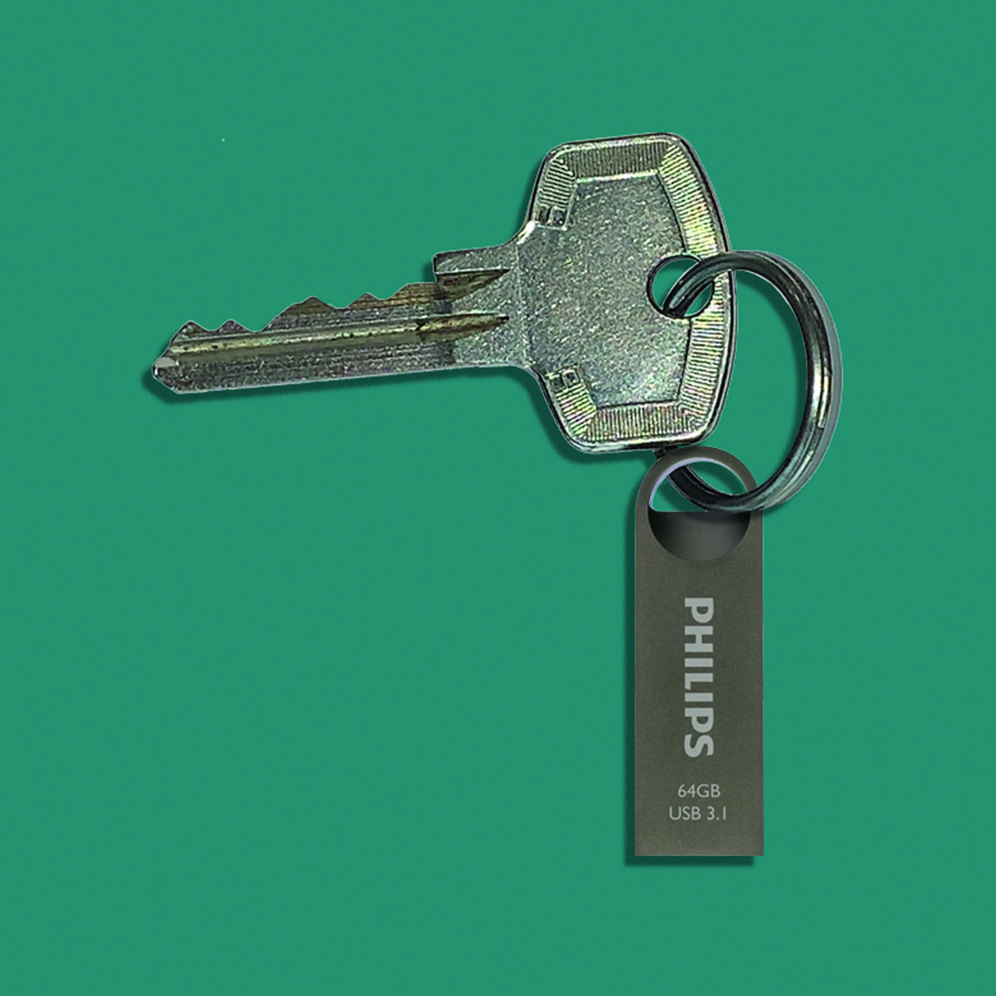 Una llave plateada y una memoria USB Philips de 64 GB cuelgan de un llavero sobre un fondo verde.