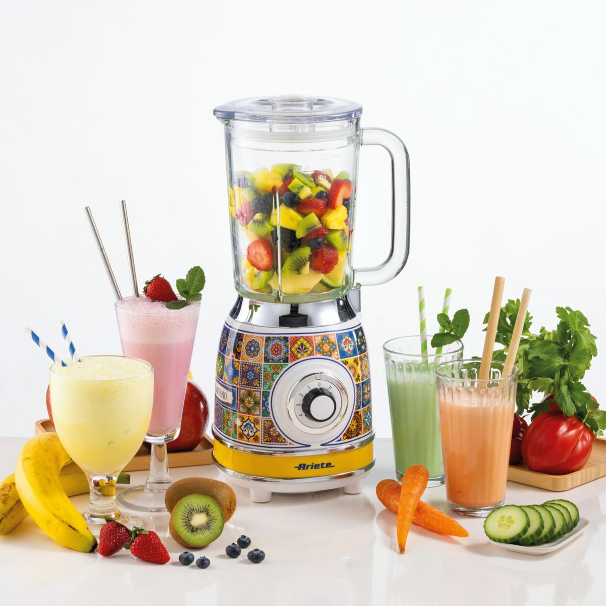 Dekoratif desenli renkli blender, taze meyve, sebze ve çeşitli meyve suları ile çevrili.