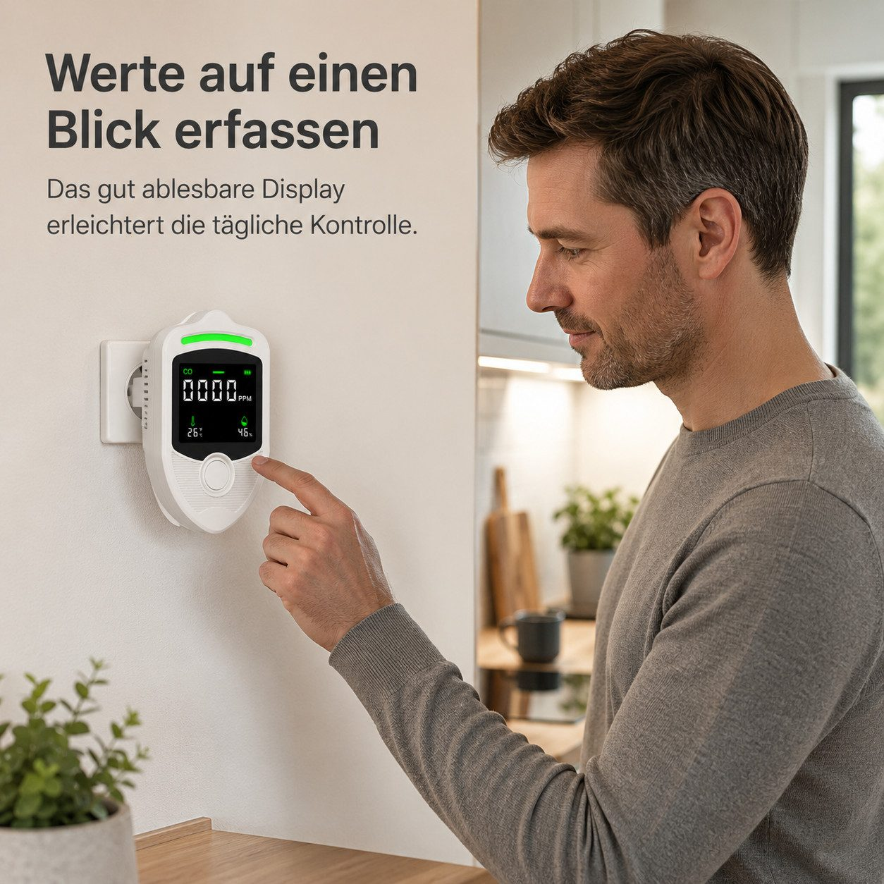 Ein Mann im grauen Pullover zeigt auf einen CO2-Monitor an der Steckdose in einem Raum.